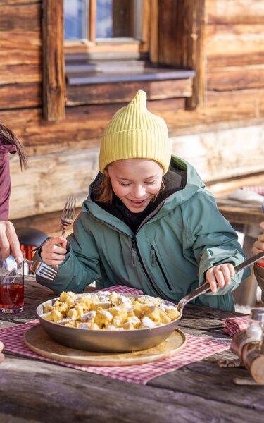 Mittagessen Familie Ski Juwel | © Ski Juwel Alpbachtal Wildschönau | Christoph Oberschneider Zwei Erwachsene und zwei Mädchen auf einer Hütte beim Kaiserschmarrn essen. | © Ski Juwel Alpbachtal Wildschönau | Christoph Oberschneider